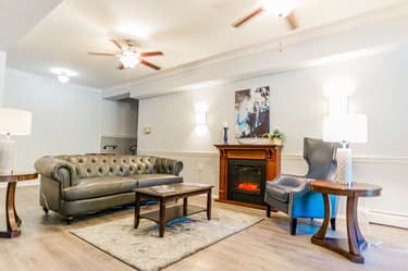 Lobby area with couch, tables, chair and fireplace. 