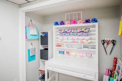 White gift wrapping station with bags, bows and wrapping paper of all colors. 